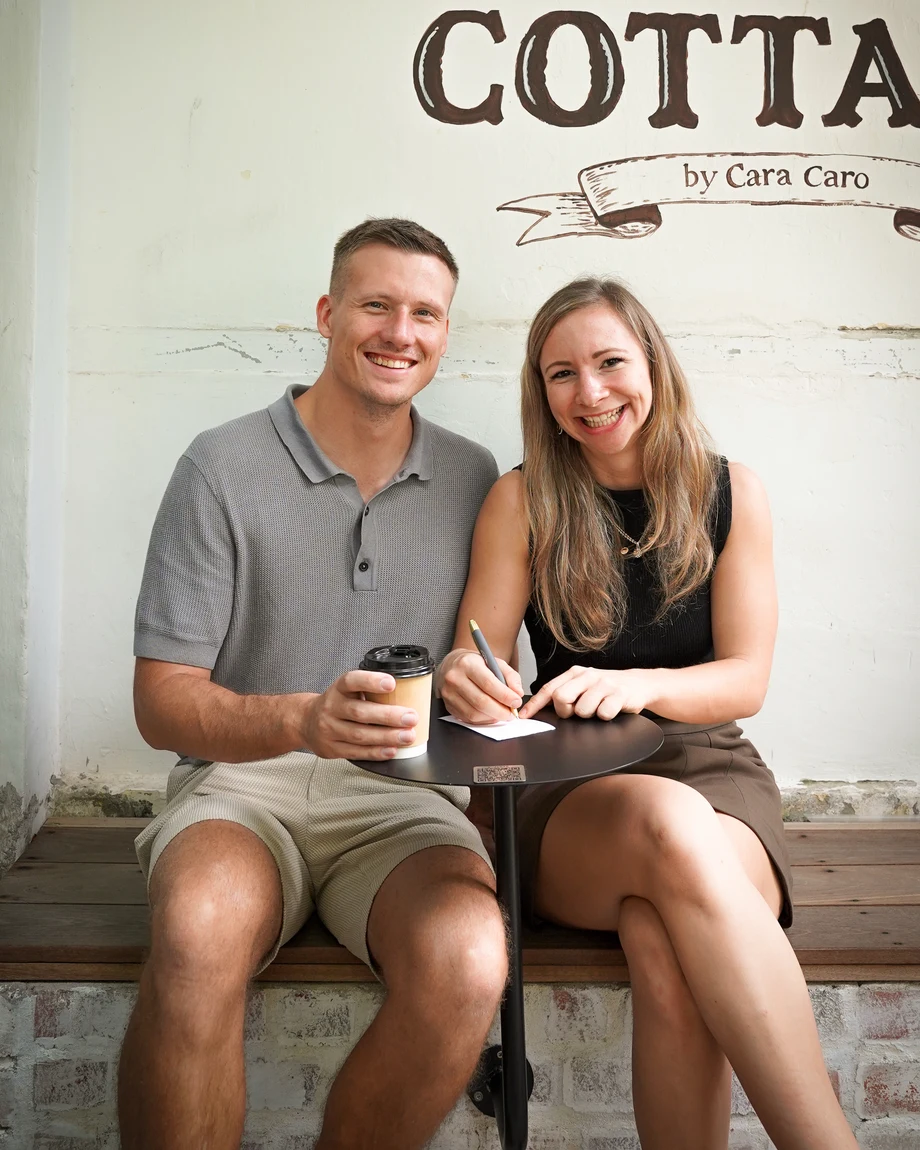 Sophie und Tobias sitzen lachend an einem kleinen Café-Tisch
